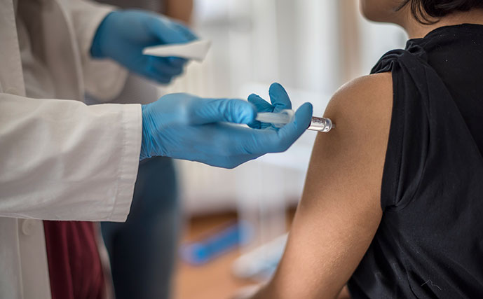 Pessoa recebendo vacina no braço por médico