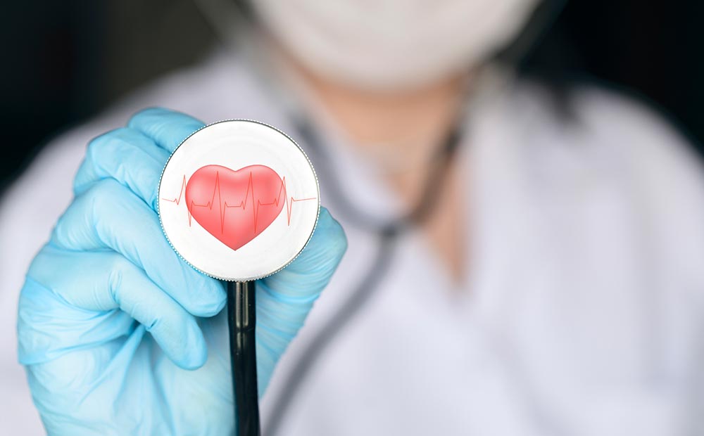 Médica segurando estetoscópio com desenho de coração como sinal de cuidados com colesterol