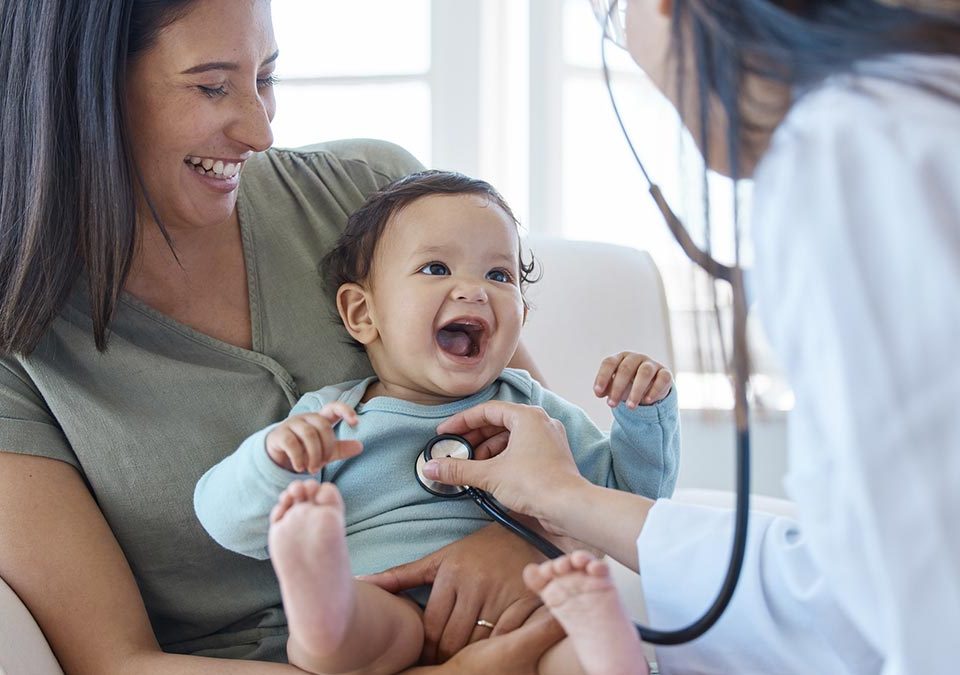 Pediatra ouvindo coração do bebê no colo da mãe
