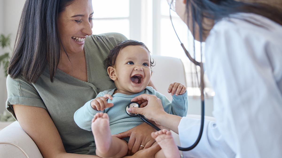 Pediatra ouvindo coração do bebê no colo da mãe