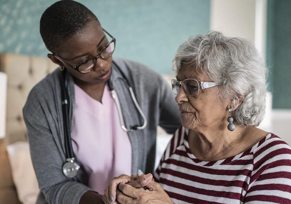 Mulher idosa com parkinson sendo cuidada pela enfermeira