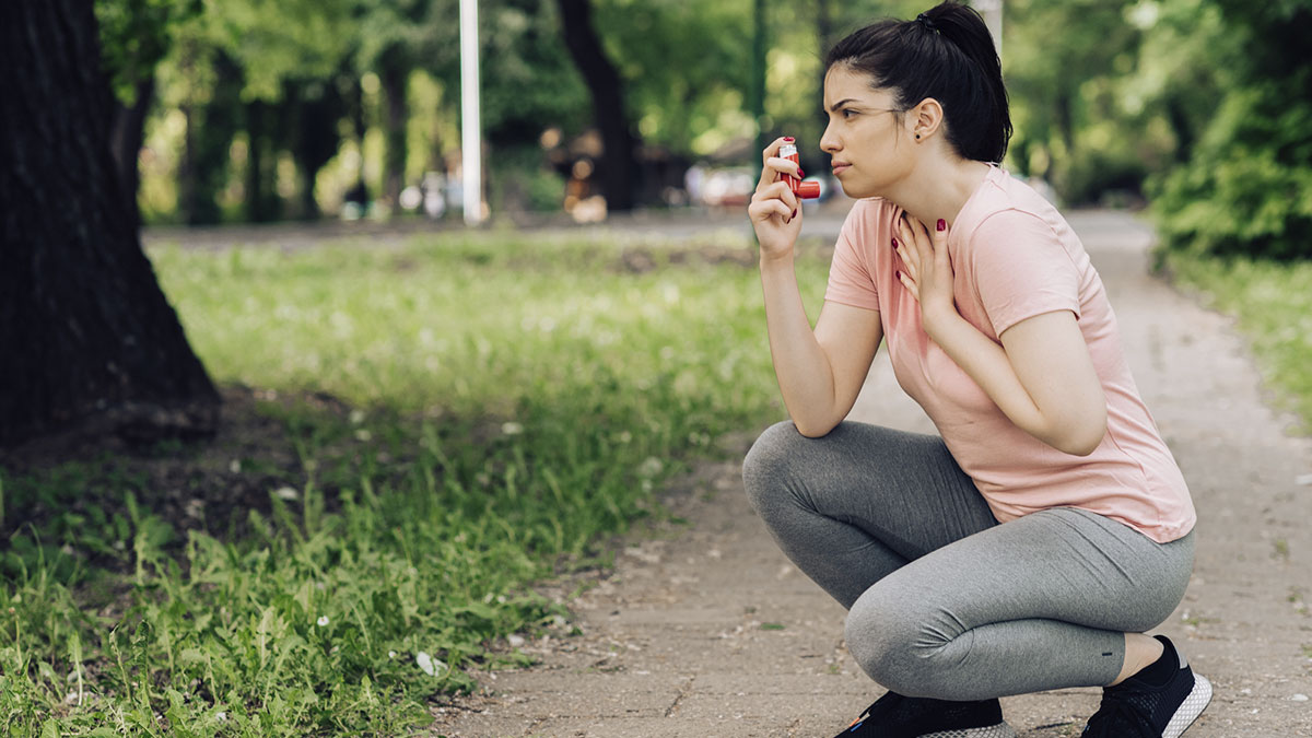 Menina usando inalador de asma durante corrida em parque