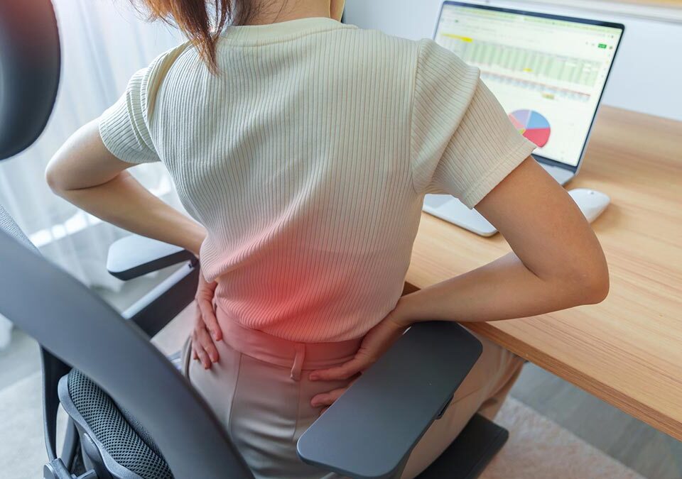 Mulher que tem dor nas costas durante o trabalho devido falta de ergonomia