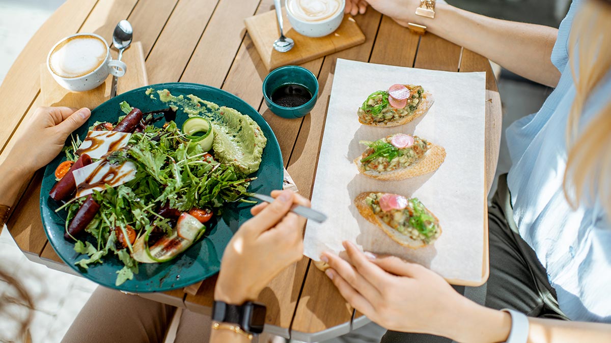 Duas pessoas sentadas comendo alimentos saudáveis