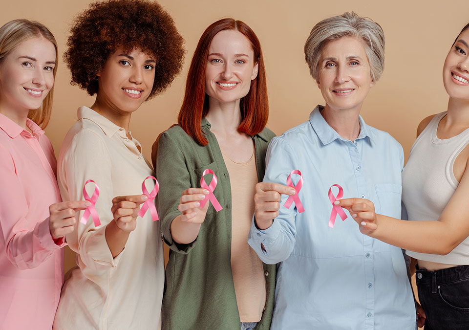 Mulheres segurando laço rosa da campanha Outubro Rosa