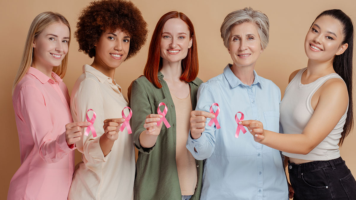 Mulheres segurando laço rosa da campanha Outubro Rosa