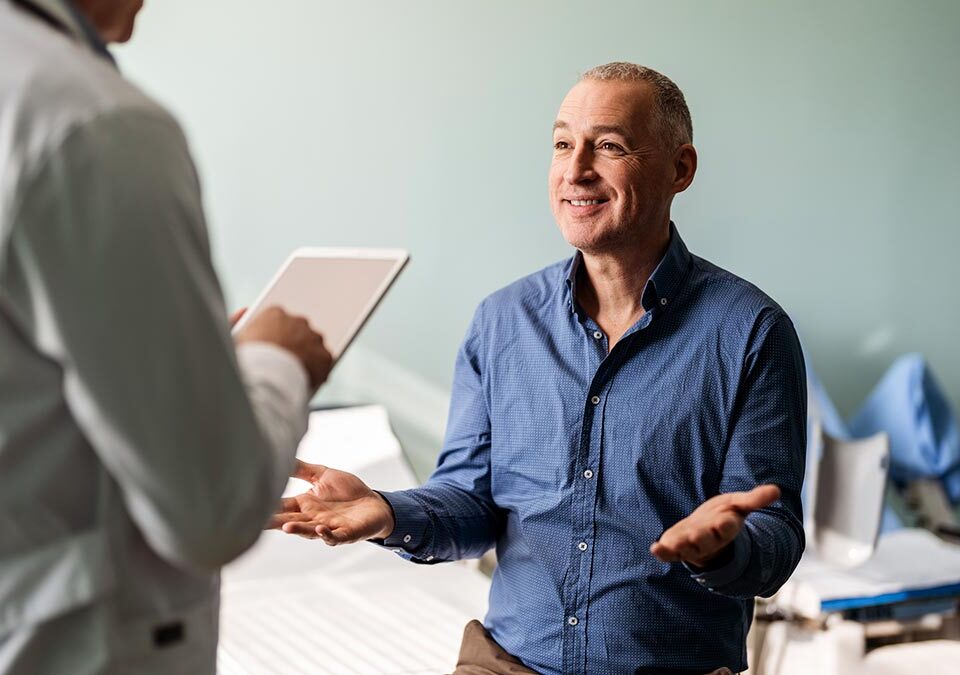 Médico conversando sobre as prevenções do câncer de próstata com homem paciente que está sentado