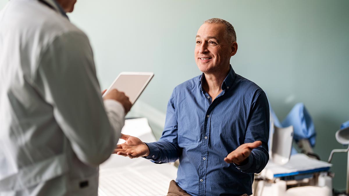 Médico conversando sobre as prevenções do câncer de próstata com homem paciente que está sentado