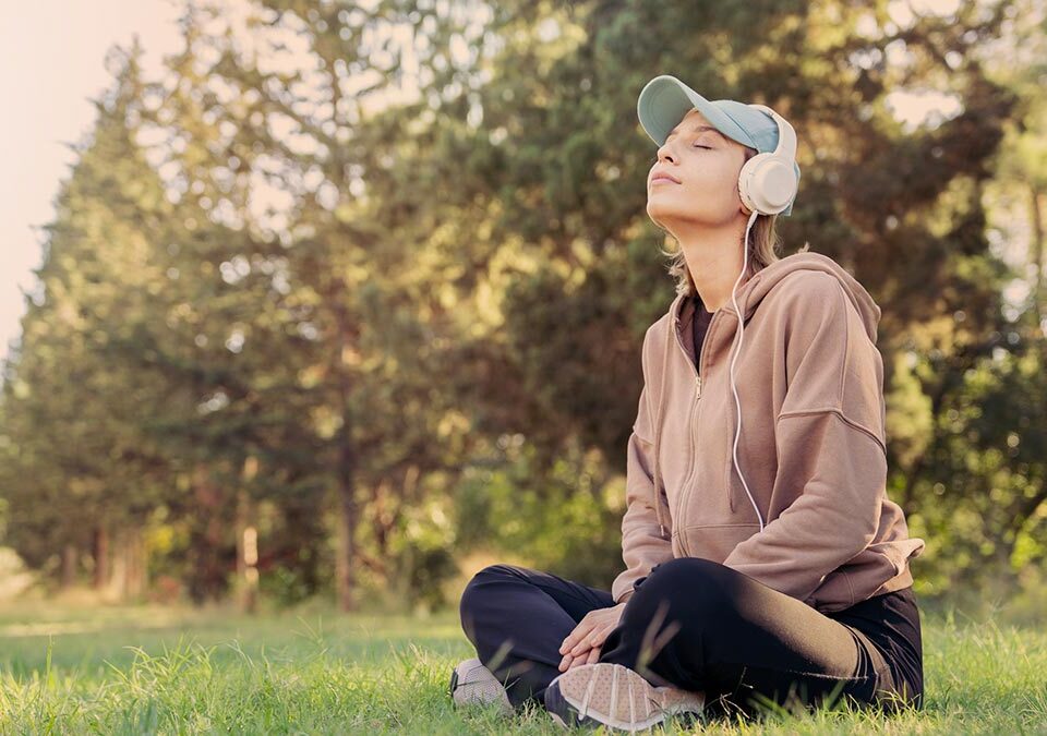 Mulher sentada no parque ouvindo música e meditando