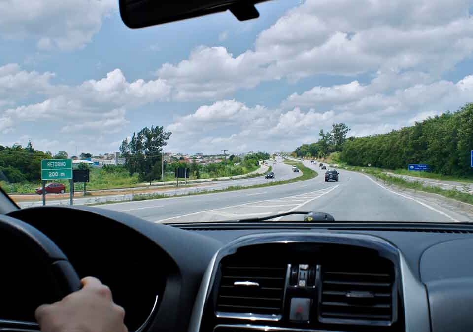Homem dirigindo e visão de dentro do carro para estrada