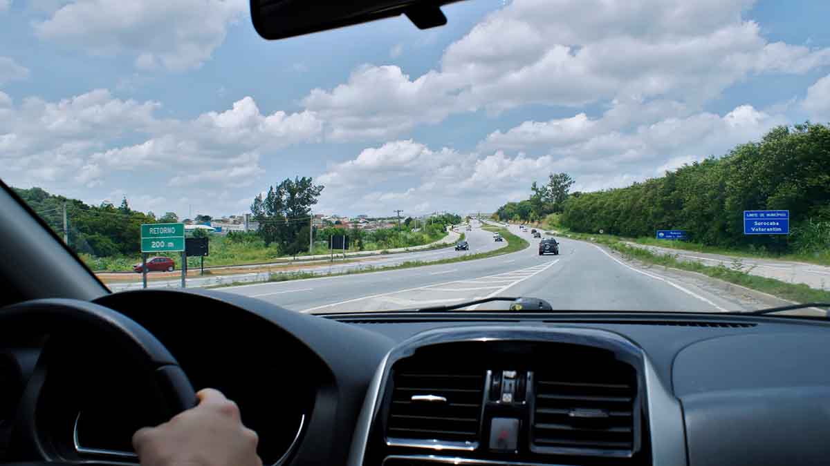 Homem dirigindo e visão de dentro do carro para estrada