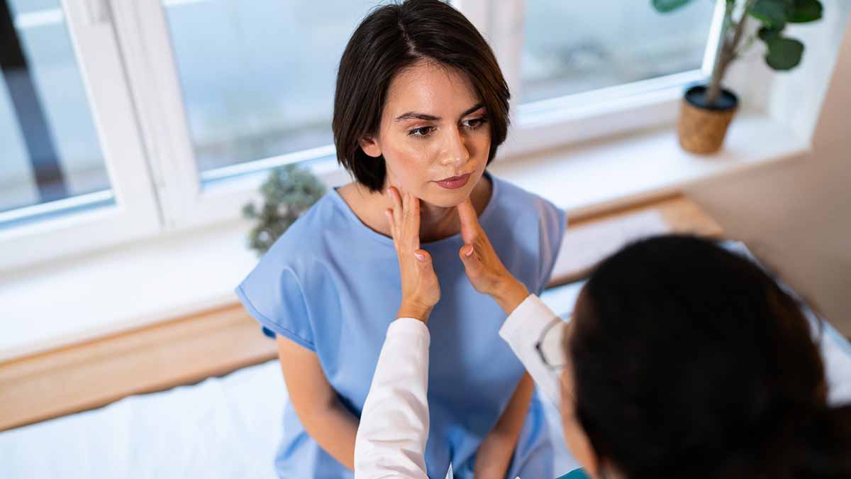 Médica examina a glândula tireoide paciente feminina