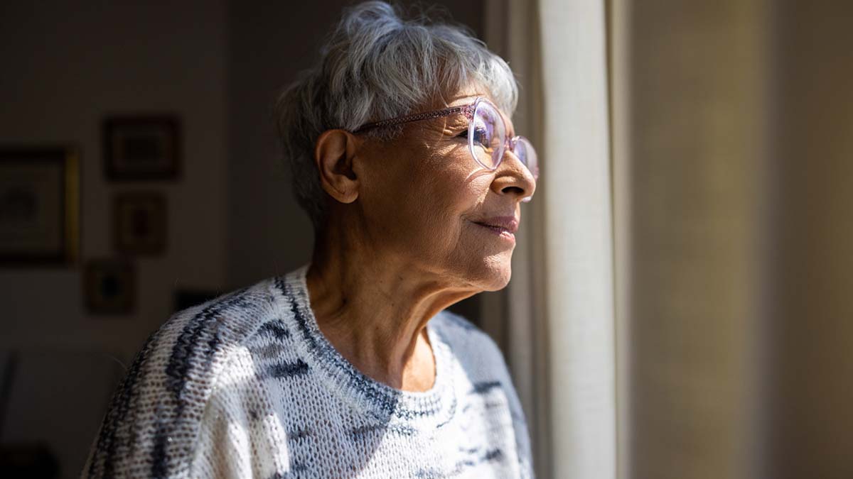 Idosa com olhando pela janela com inicio de Alzheimer