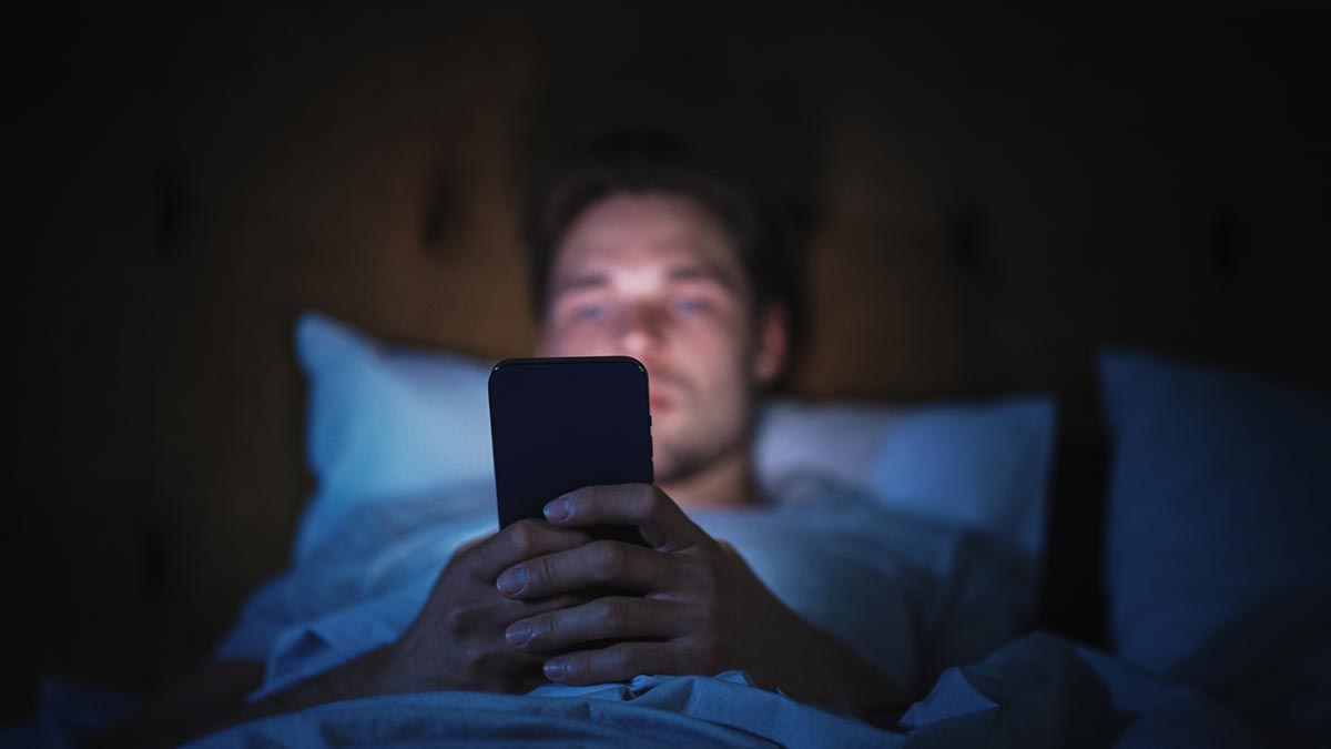 Utilizando celular na cama antes de dormir